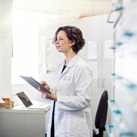 Frau in Apotheke schaut auf Tablet