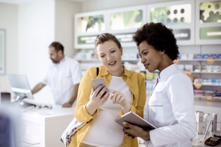 Eine Frau zeigt in der Apotheke ihr Handy 